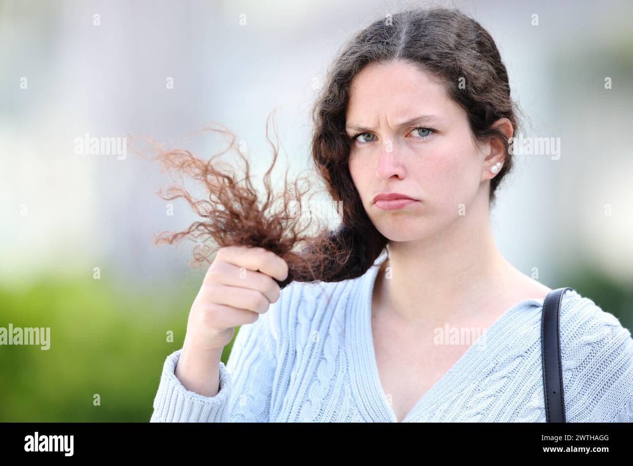Enttäuschte Frau, die Haare hält und dich auf der Straße ansieht Stockfoto