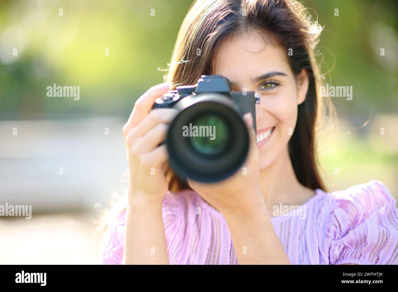 Porträt eines glücklichen Fotografen, der Sie in einem Park fotografiert Stockfoto
