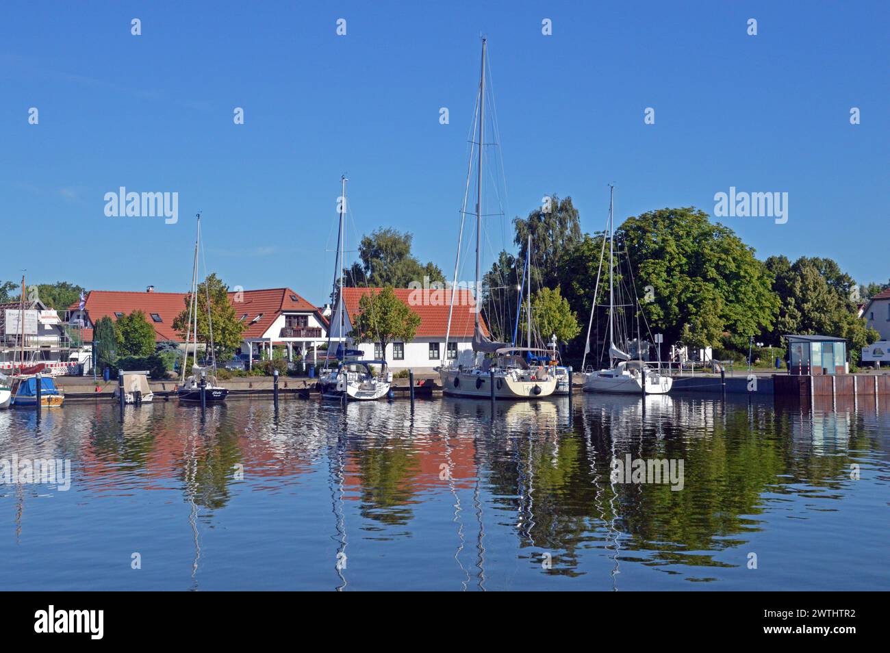 Deutschland, Mecklenburg-Vorpommern, Greifswald (Hansestadt): Yachten, die in Wieck, einem Teil von Greifswald, verankert sind, spiegeln sich im Wasser des Flusses Ryck. Stockfoto