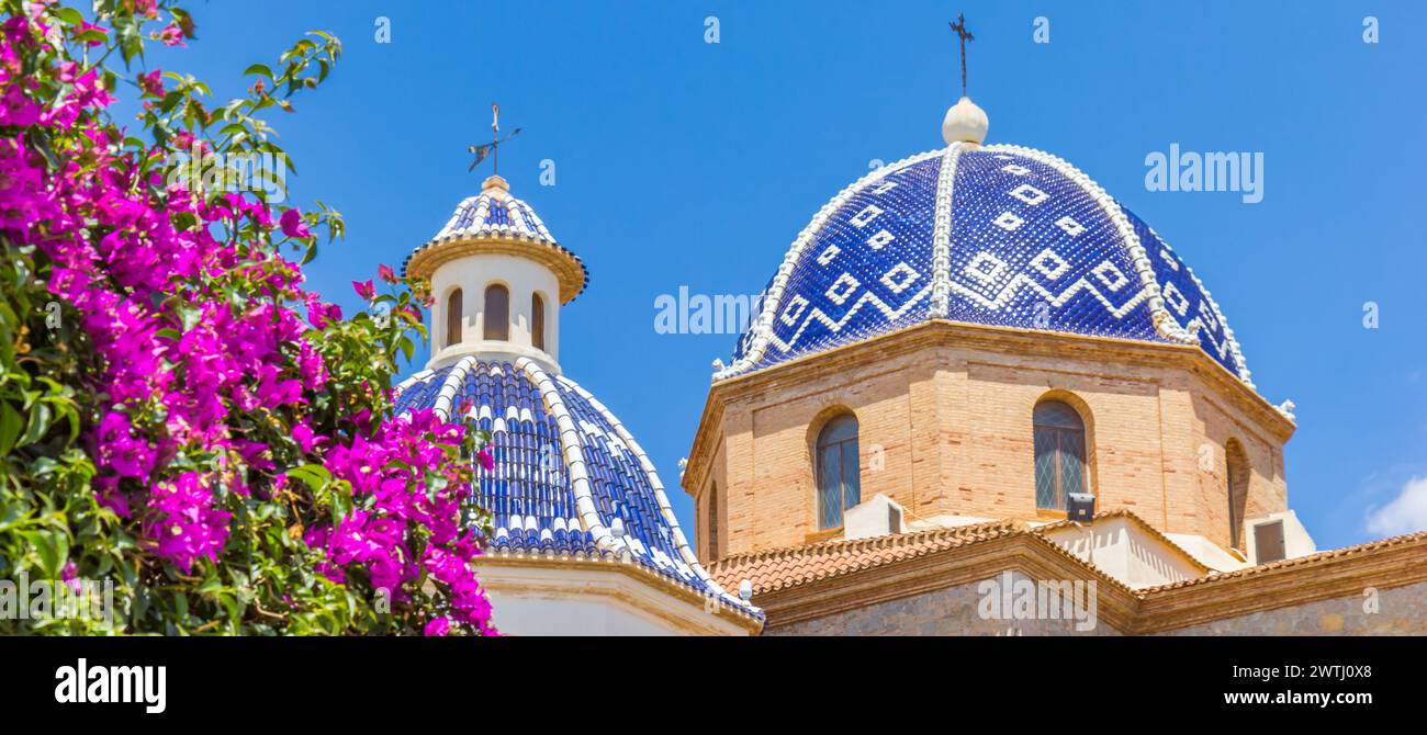 Panorama der violetten Blumen vor der blau gekachelten Kuppel der Kirche in Altea, Spanien Stockfoto