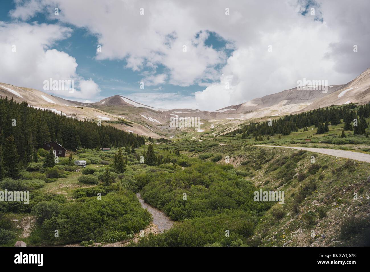 Ein malerischer Blick auf das Colorado Mountain Valley mit einem Kamm im Frühjahr mit einer unbefestigten Straße und einem Bach Stockfoto