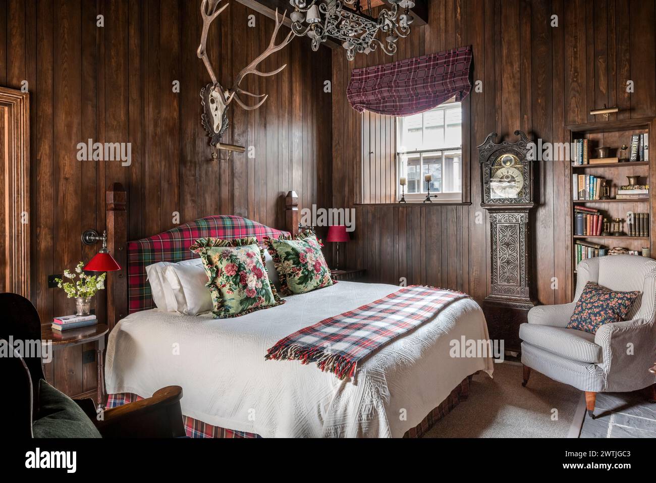 Wandgeweih über dem Bett mit Schottendecke in einem Luxushotel in Ardfin auf der Isle of Jura, Innere Hebriden, Schottland, Großbritannien Stockfoto