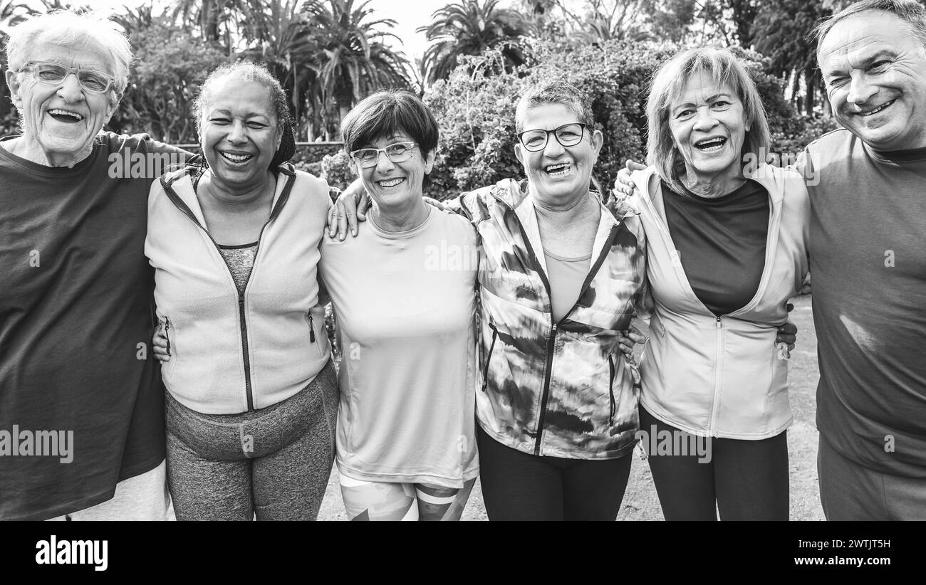 Multiethnische Senioren, die nach dem Training Spaß haben, trainieren im Freien mit Stadtpark im Hintergrund - gesunder Lebensstil und fröhlicher Lebensstil älterer Menschen con Stockfoto