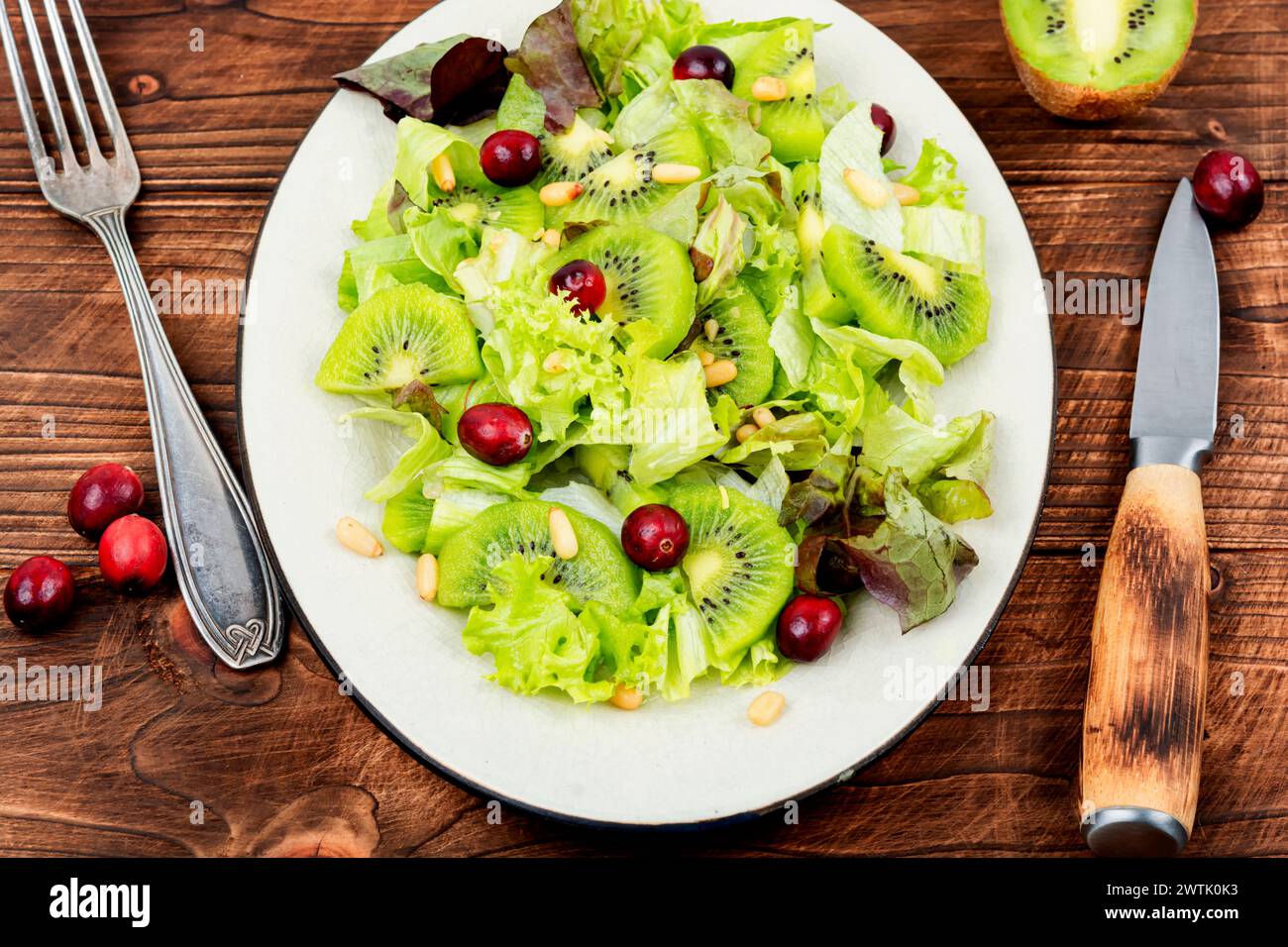 Vitaminsalat aus Kiwi, Grün, Beeren und Pinienkernen auf Holztisch. Sauberes Essen. Stockfoto