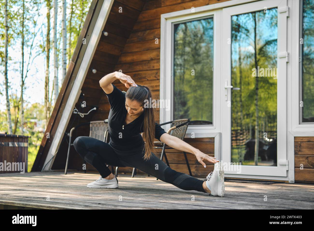 Sportliche Frau, die seitliche Pisten auf der Terrasse des Bungalows macht Stockfoto