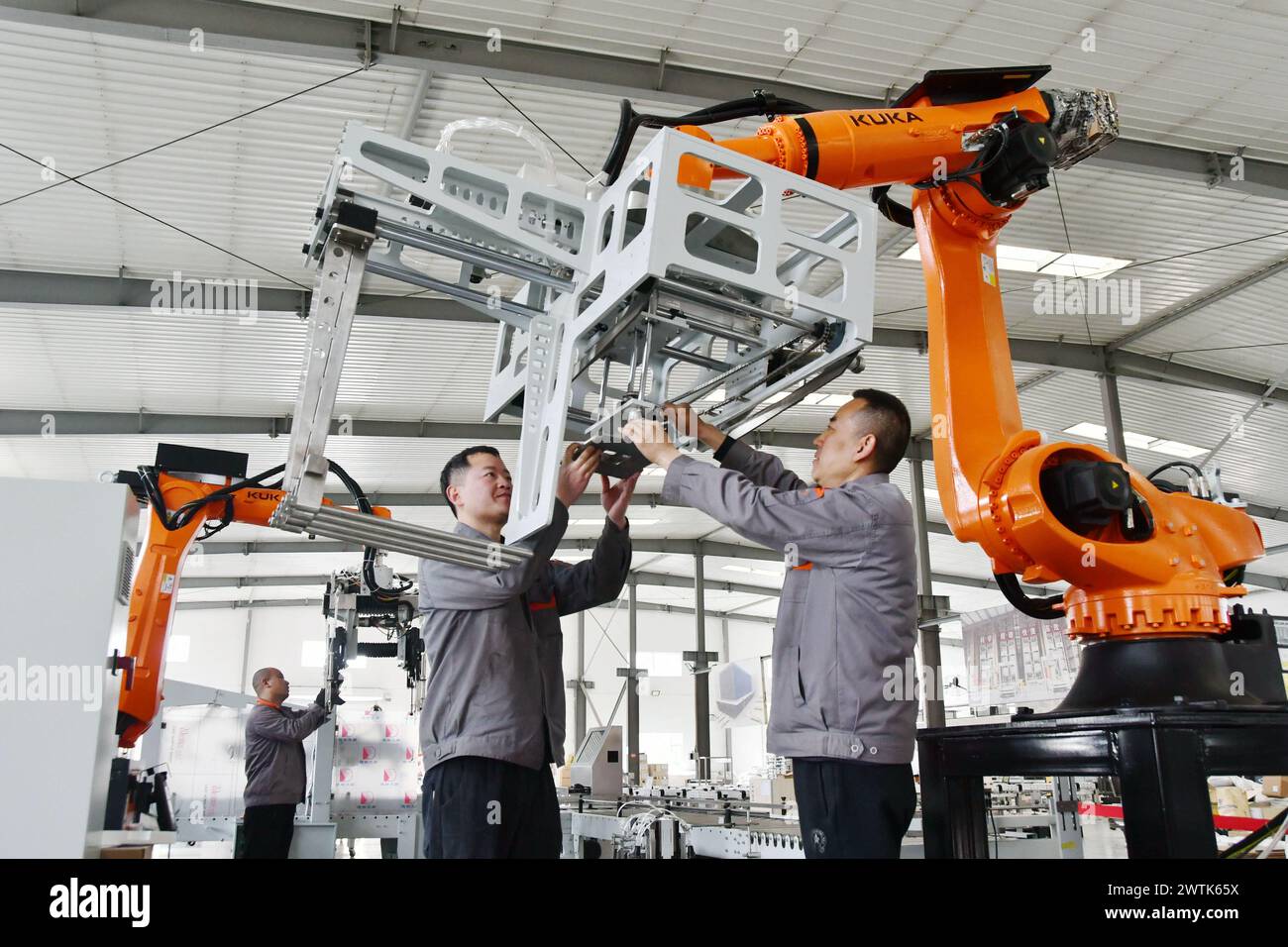 HANDAN, CHINA – 18. MÄRZ 2024 – zwei Mitarbeiter installieren in einer Werkstatt eines intelligenten Geräteunternehmens in Han einen Industrieroboter Stockfoto