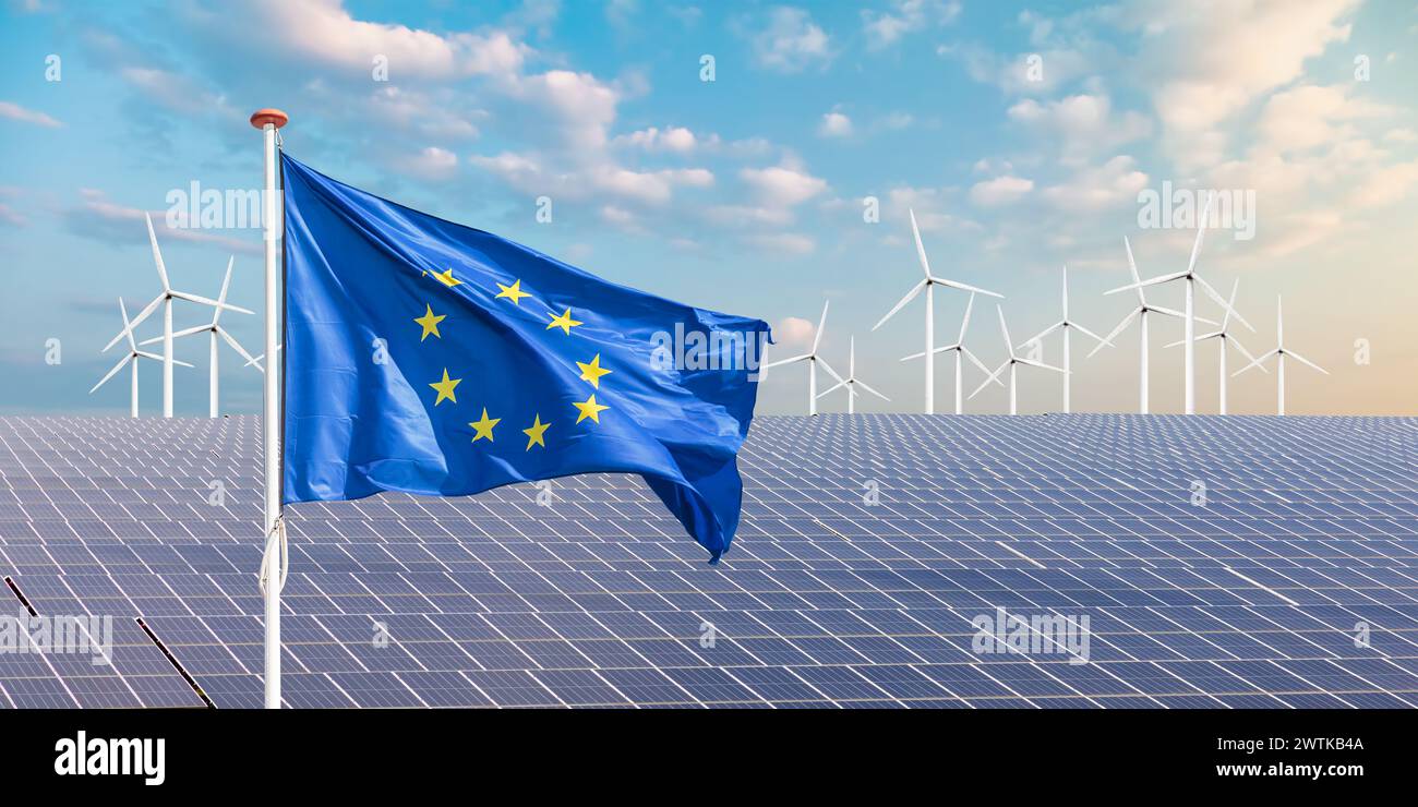 Offizielle Flagge der Europäischen Union vor einer Vielzahl von Solarpaneelen und Windturbinen Stockfoto