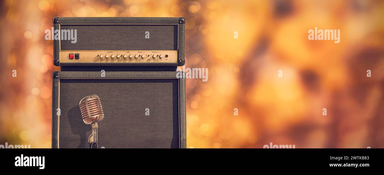 Großer Gitarrenverstärker Lautsprecherschrank und Bedienkopf mit Vintage-Mikrofon vor einem farbenfrohen Hintergrund mit Kopierraum Stockfoto