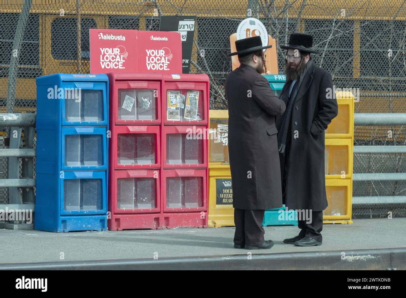 2 orthodoxe jüdische Männer - enge Sprecher - sprechen vor einem bunten Hintergrund. An der Bedford Avenue in Williamsburg, Brooklyn, New York. Stockfoto