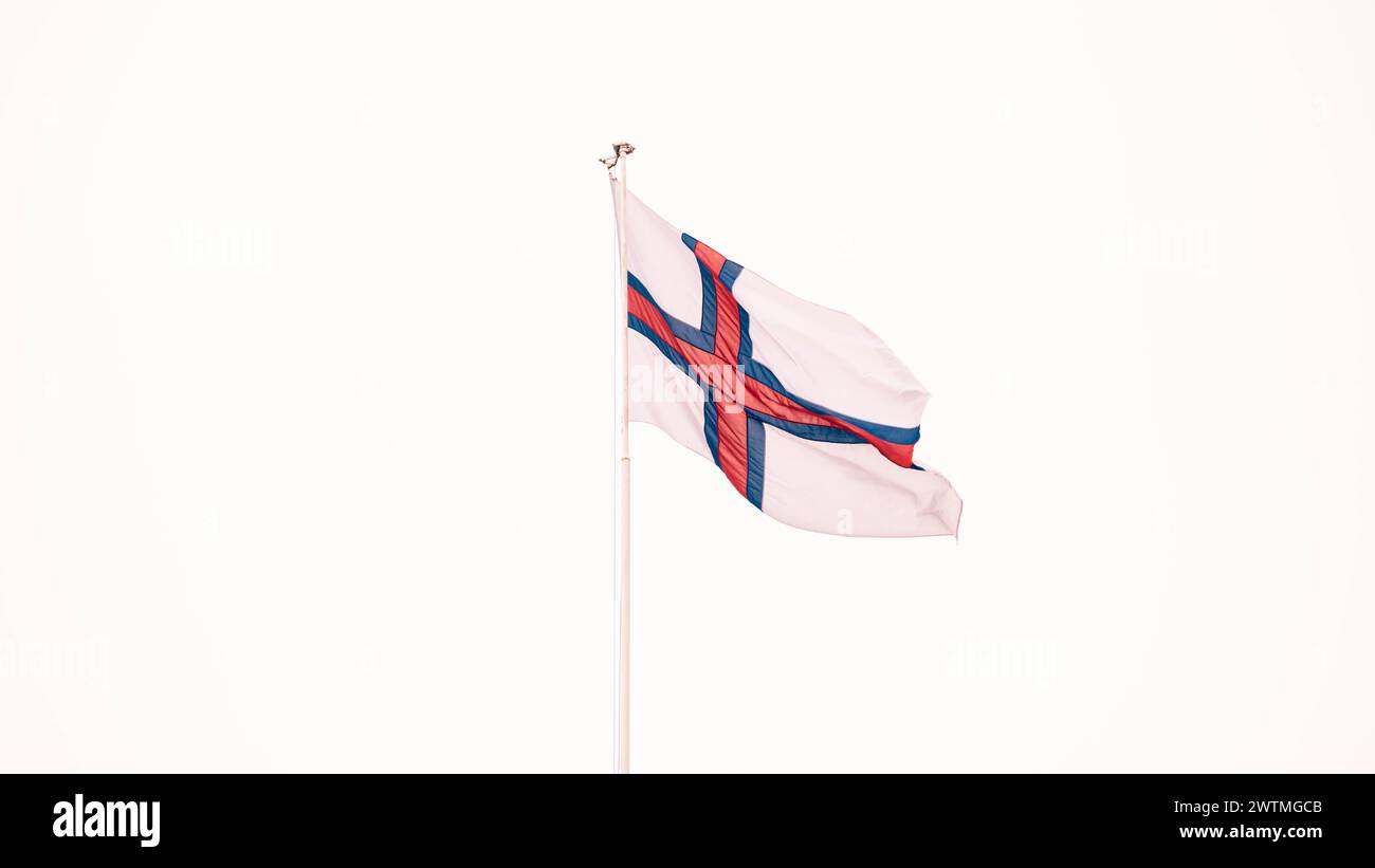 Die färöische Flagge auf einem Fahnenmast hört auf zu winken, weil es in der Nähe des Parlaments von Torshavn Tinganes, Wolke, Foroyar, 4K keinen Wind mehr gibt Stockfoto