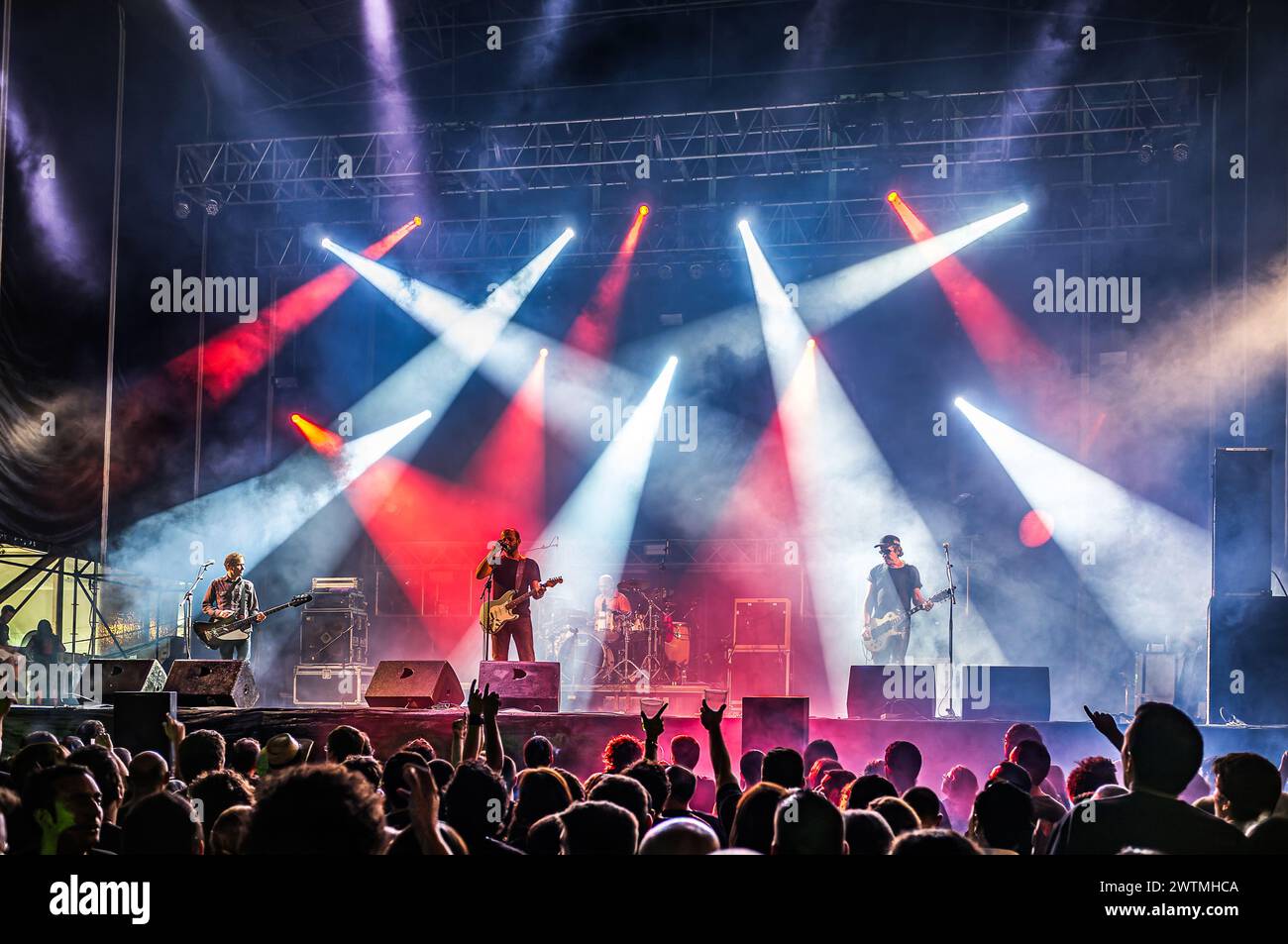 Los Enemigos tritt live auf der Bühne mit lebhaften Lichtern und einer engagierten Menge auf. Stockfoto