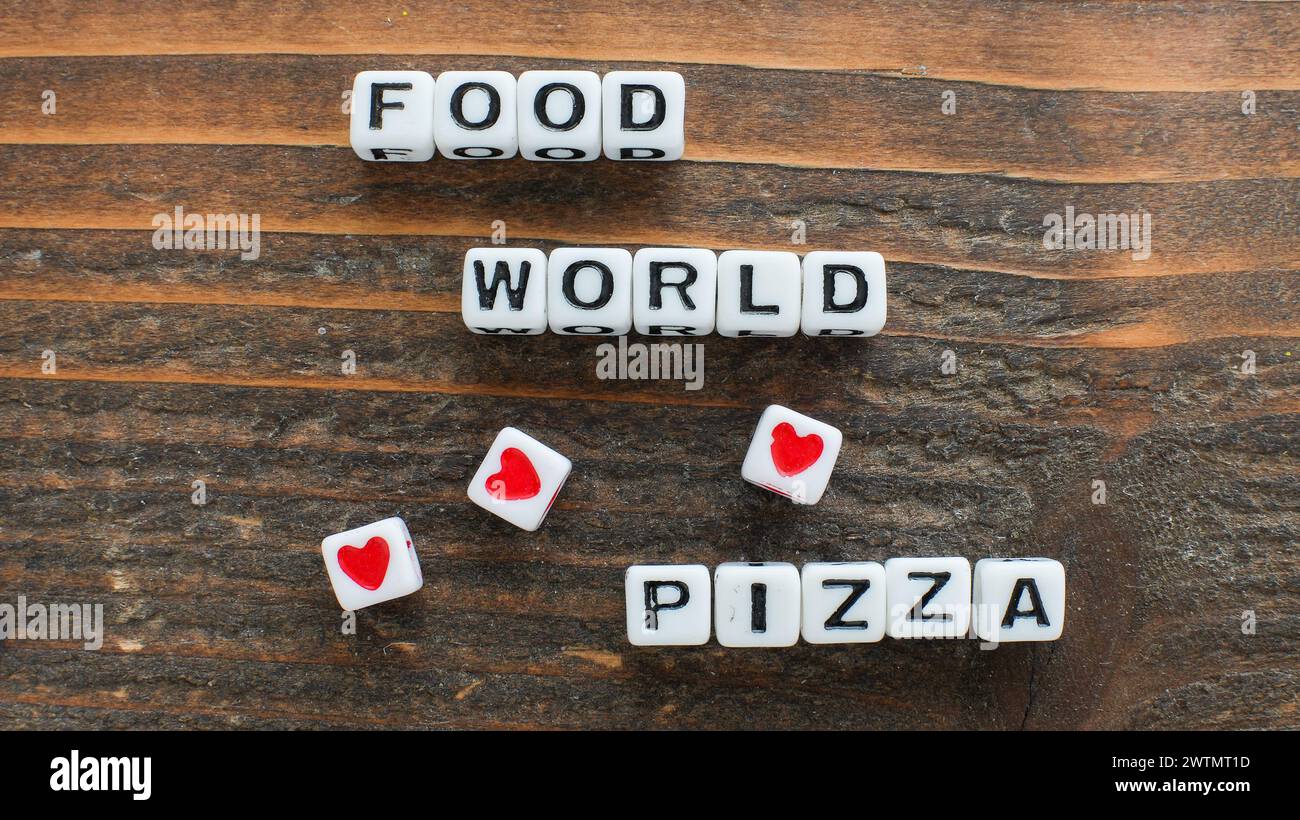 Verschiedene Buchstabenwürfel, die kunstvoll angeordnet sind, um die Botschaft Food Loves World Pizza vor der reichhaltigen Textur eines hölzernen Hintergrunds zu beschreiben Stockfoto