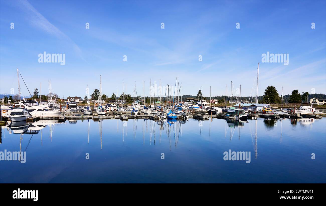 Blick auf die kleinen Motorboote und Segelschiffe, die an einem hellen Frühlingstag in der Deep Bay Marina, Vancouver Island, BC, vor Anker gebracht werden. Stockfoto