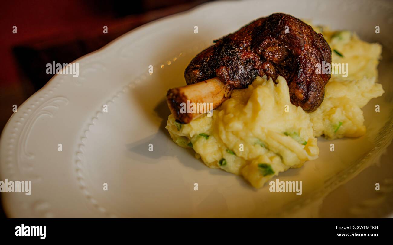 Saftige gebackene Lammshank serviert auf cremigem Kartoffelpüree auf einem weißen Teller. Stockfoto