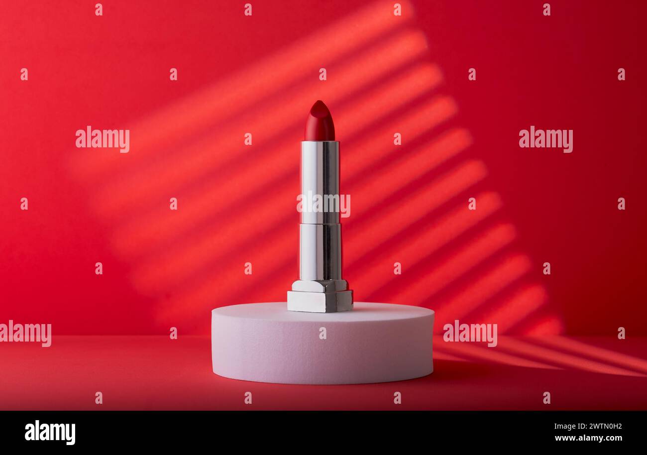 Eleganter roter Lippenstift mit einem coolen, modernen roten Hintergrund. Stockfoto