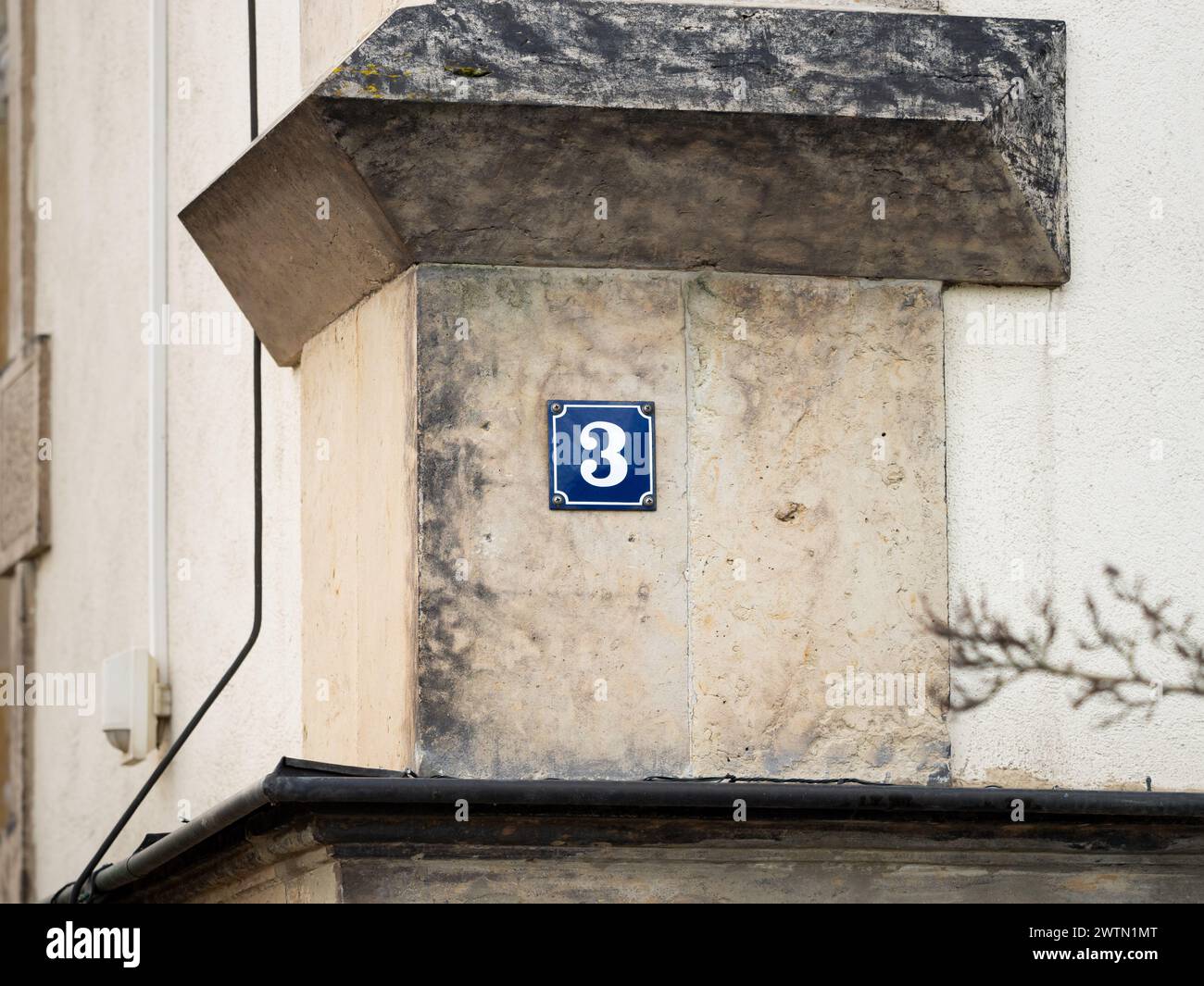 Nummer 3 an einer Hauswand. Die Metallplatte ist emailliert und in blauer Farbe. Das Design ist sehr Vintage und Retro. Die drei sind auch eine Primzahl Stockfoto