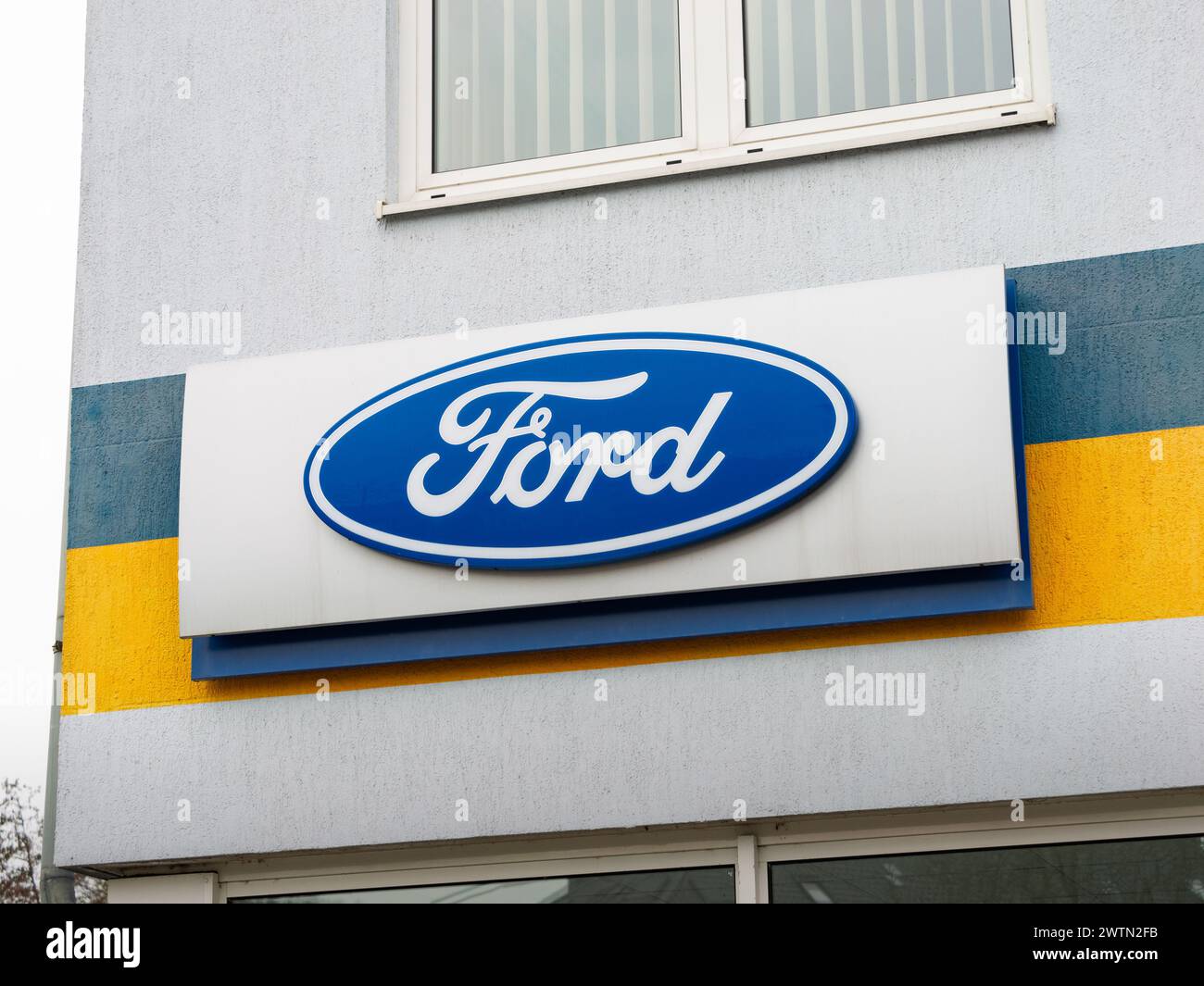 Ford-Emblem an der Gebäudefassade eines Autohändlers. Das Symbol der amerikanischen Marke ist eine große Werbung. Logozeichen des beliebten Automobilunternehmens. Stockfoto