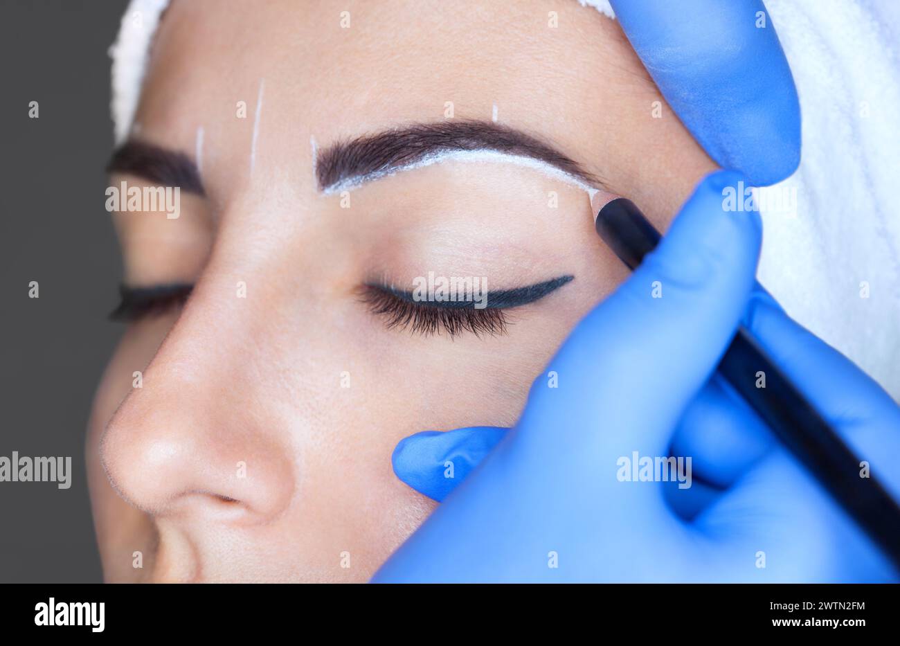 Permanent Make-up für Augenbrauen einer schönen Frau mit dicken Augenbrauen im Schönheitssalon. Nahaufnahme-Kosmetikerin, die Augenbrauen tätowiert. Stockfoto