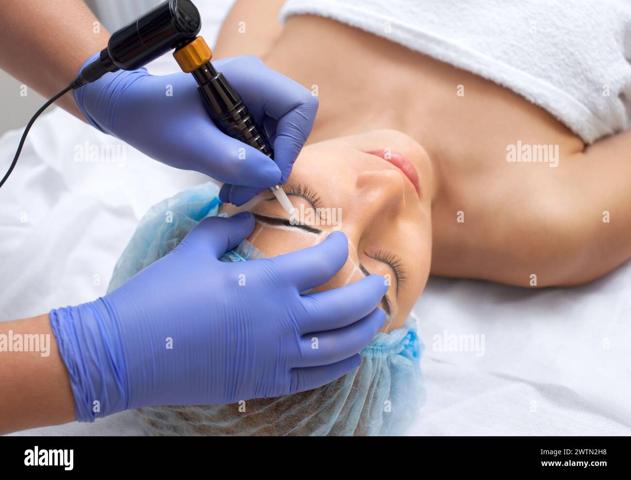 Permanent Make-up für Augenbrauen einer schönen Frau mit dicken Augenbrauen im Schönheitssalon. Nahaufnahme-Kosmetikerin, die Augenbrauen tätowiert. Stockfoto