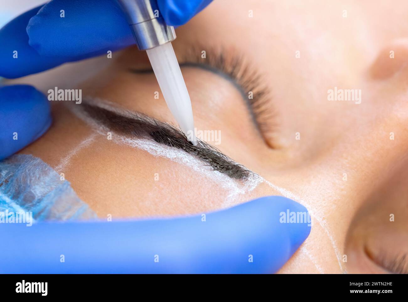 Permanent Make-up für Augenbrauen einer schönen Frau mit dicken Augenbrauen im Schönheitssalon. Nahaufnahme-Kosmetikerin, die Augenbrauen tätowiert. Stockfoto