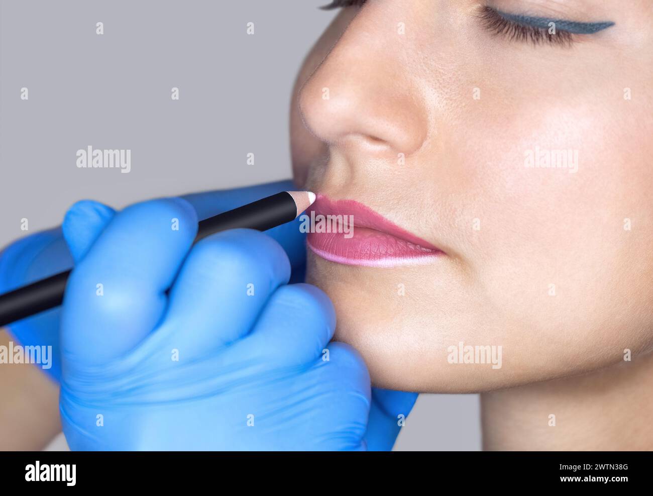 Permanentes Make-up für rote Lippen der schönen Frau im Schönheitssalon. Nahaufnahme-Kosmetikerin, die Lippen tätowiert. Stockfoto