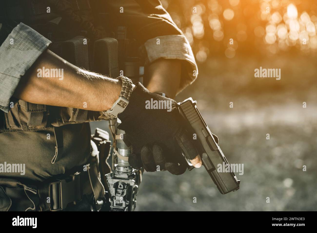 Der Soldat bei der Ausführung von Aufgaben in Tarnhülle und Schutzhandschuhen mit Pistole. Kriegsgebiet. Stockfoto