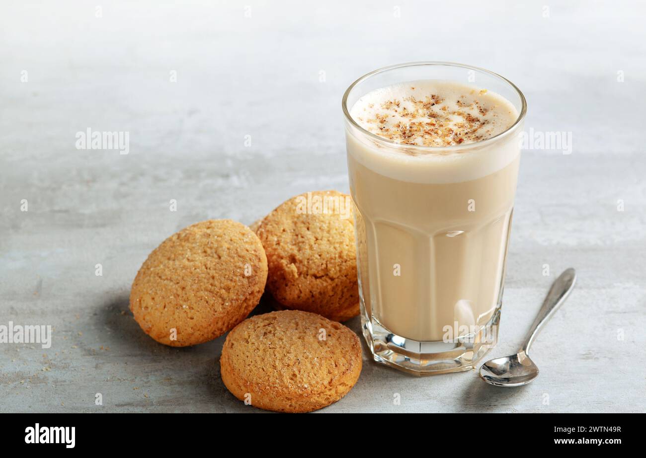Kaffee-Raff in einem Glas Nahaufnahme mit hausgemachten Keksen. Kaffee mit Milch und geriebener Nuss auf hellem Hintergrund Stockfoto