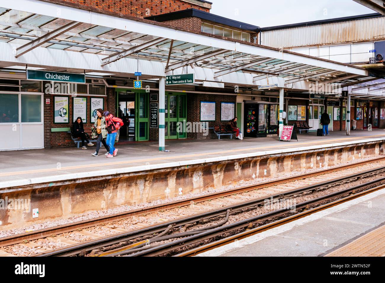 Passagiere, die auf dem Bahnsteig warten. Bahnhof Chichester. Chichester, West Sussex, South East, England, Vereinigtes Königreich, Europa Stockfoto