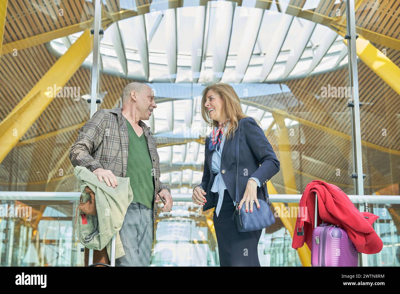 Reisenpaar mittleren Alters, das sich am Busbahnhof oder Flughafen unterhalten und auf eine Reise oder Flitterwochen wartet Stockfoto