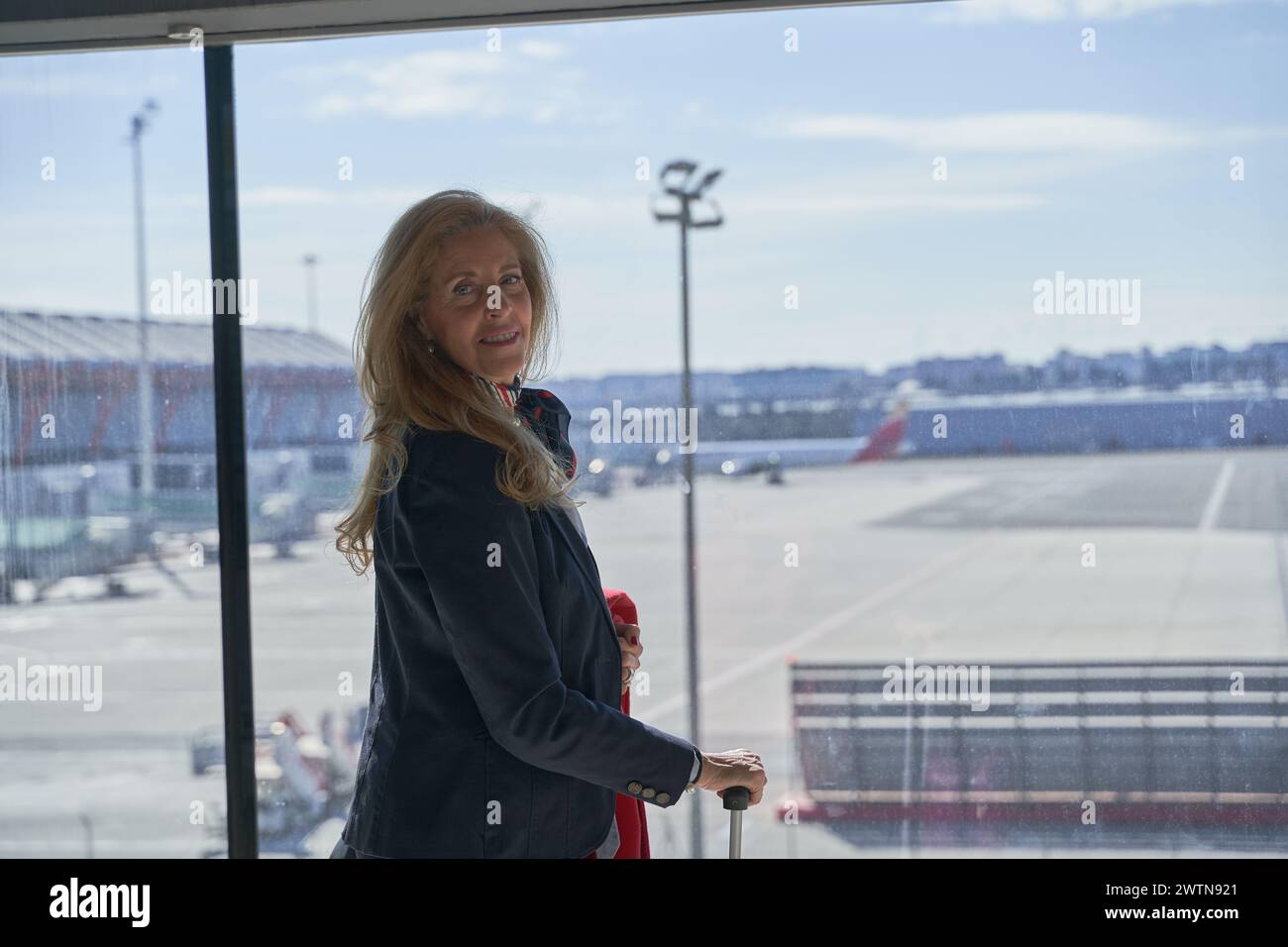 Eine hübsche Frau mittleren Alters wartet auf das Boarding im Flughafenterminal. Stockfoto