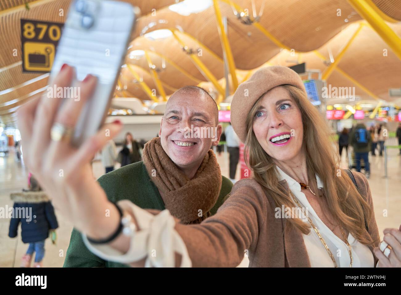 Urlaub Selfie. Wunderschönes, liebevolles Paar mittleren Alters, das Selfie mit ihrem Smartphone macht, während es auf das Boarding am Flughafen wartet. Stockfoto