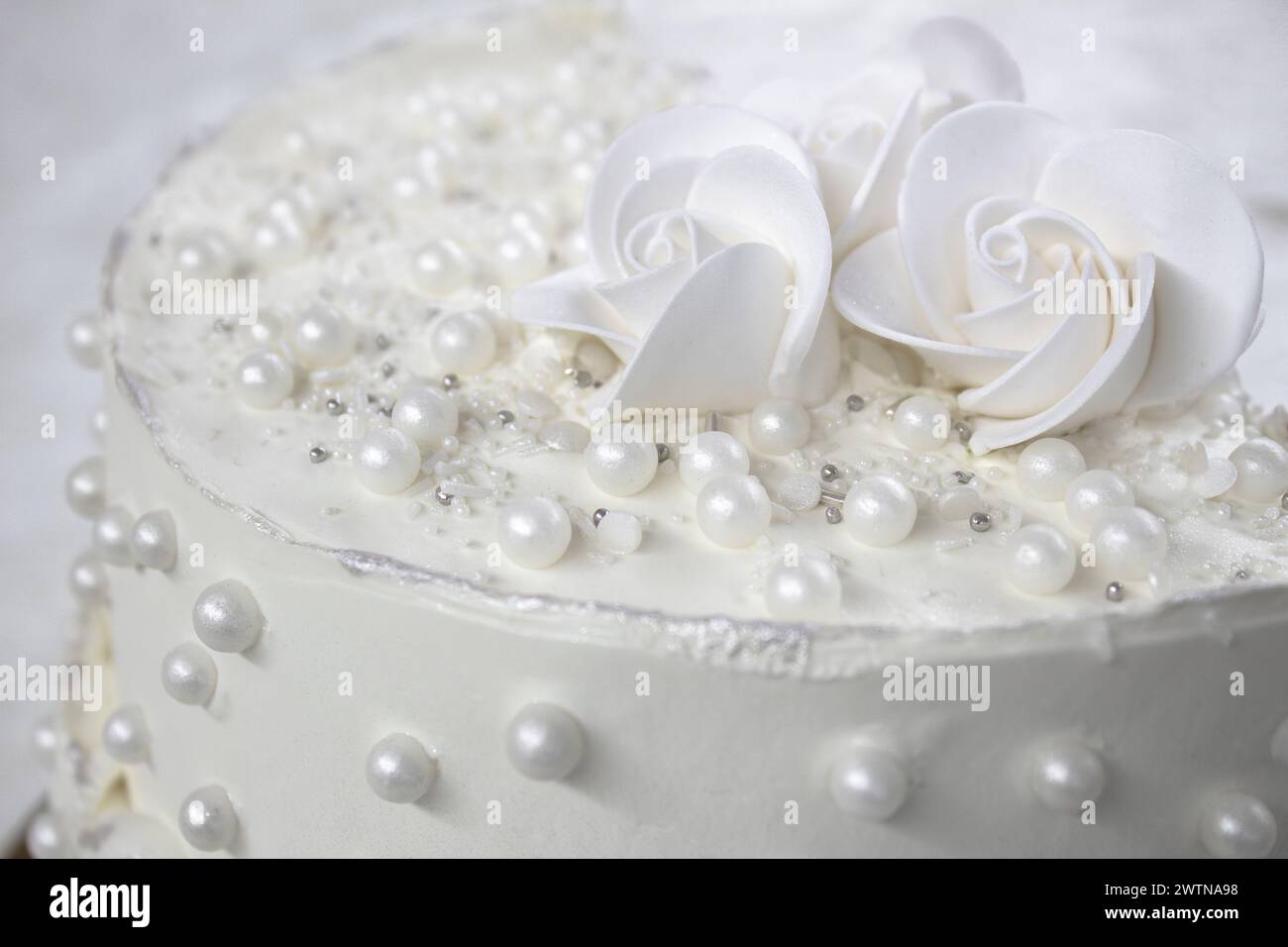 Weißer Partykuchen mit weißer Glasur und Perlen, Kuchendesign. Handgemachter Kuchen für einen besonderen feierlichen Anlass. Besondere Details. Stockfoto