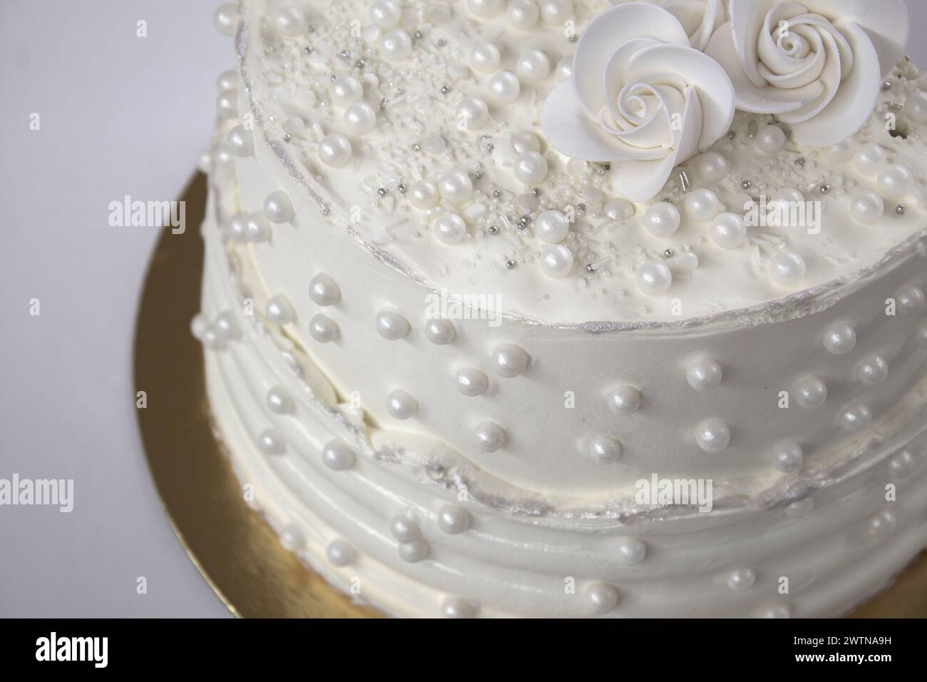 Weißer Partykuchen mit weißer Glasur und Perlen, Kuchendesign. Handgemachter Kuchen für einen besonderen feierlichen Anlass. Besondere Details. Stockfoto