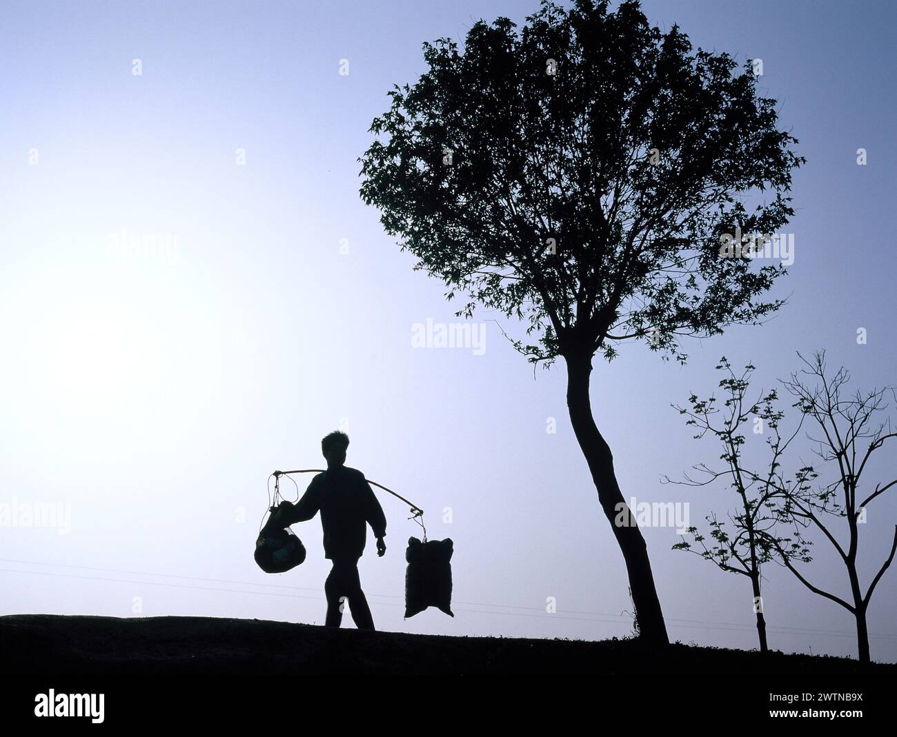 China. Jiangsu. Die Silhouette eines einheimischen Mannes, der Bündel trägt. Stockfoto
