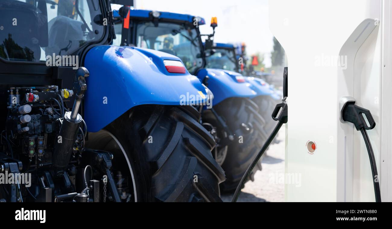 Ladestation für Elektrofahrzeuge vor dem Hintergrund landwirtschaftlicher Traktoren. Konzept Stockfoto