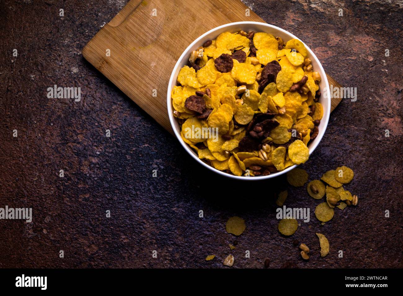 Knusprige Flocken zum Frühstück in einer weißen Schüssel auf hölzernem Hintergrund. Selektiver Fokus. Stockfoto