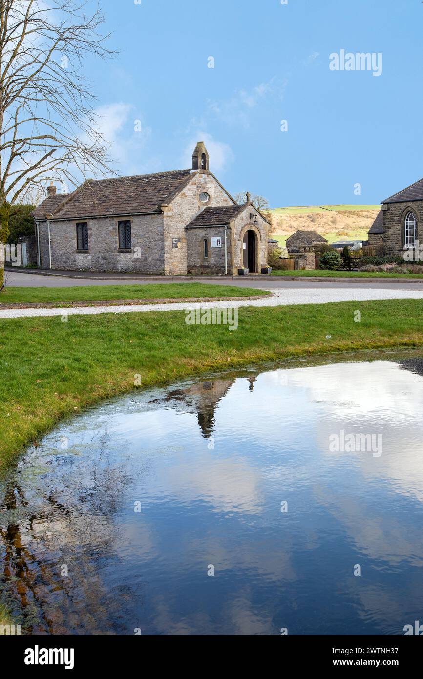 Die Pfarrkirche St Hugh's Church befindet sich auf der anderen Seite des Dorfteichs im Derbyshire Peak District Village Foolow Stockfoto