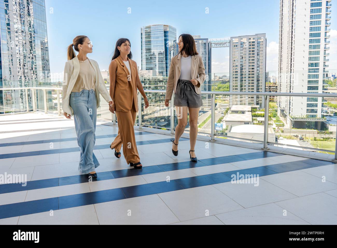 Drei Geschäftsfrauen laufen auf der Terrasse eines Turmgebäudes Stockfoto