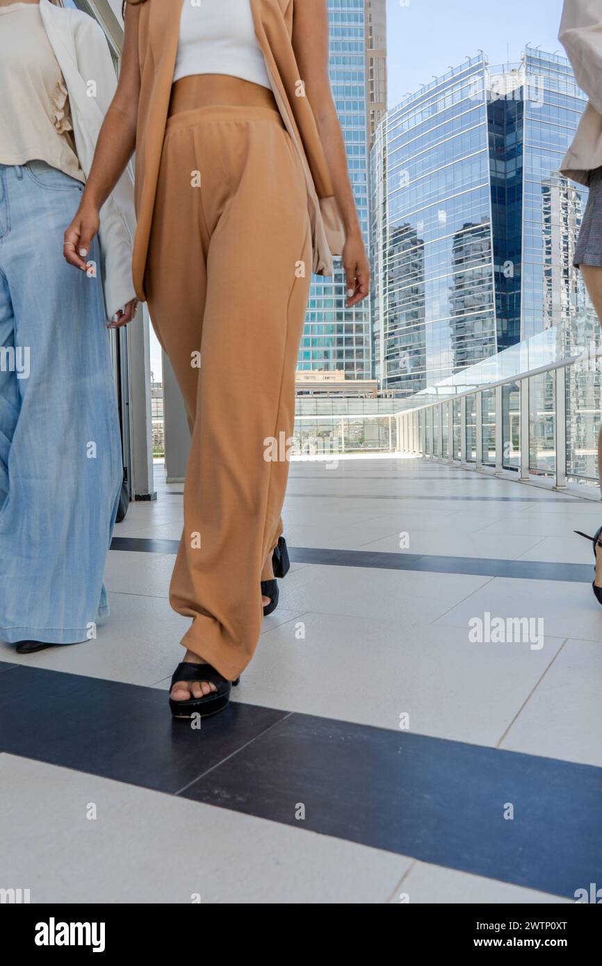 Nahaufnahme der Beine von Geschäftsfrauen, die auf einem Bürgersteig vor einem hohen Gebäude laufen. Die Szene strahlt weibliche Ermächtigung in der Geschäftswelt aus. Stockfoto