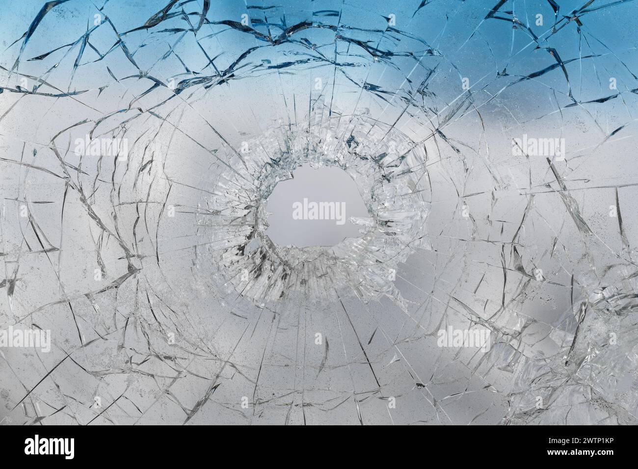 Ein Schussloch in einem getönten Glas aus der Nähe eines Autos. Stockfoto