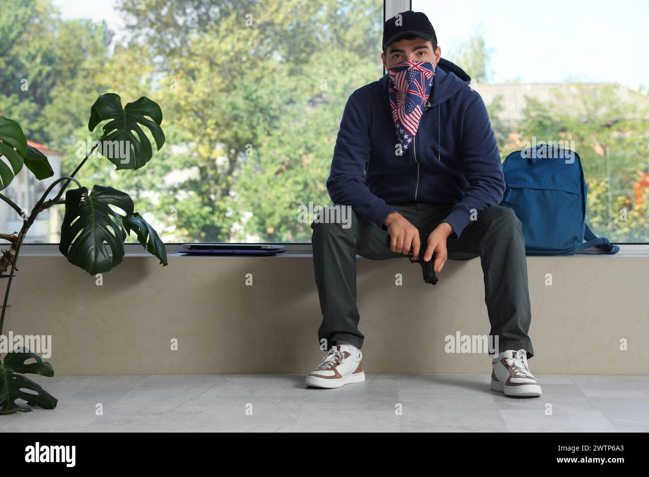 Männlicher Student mit Waffe sitzt an der Universität. Aufnahmeproblem Konzept Stockfoto