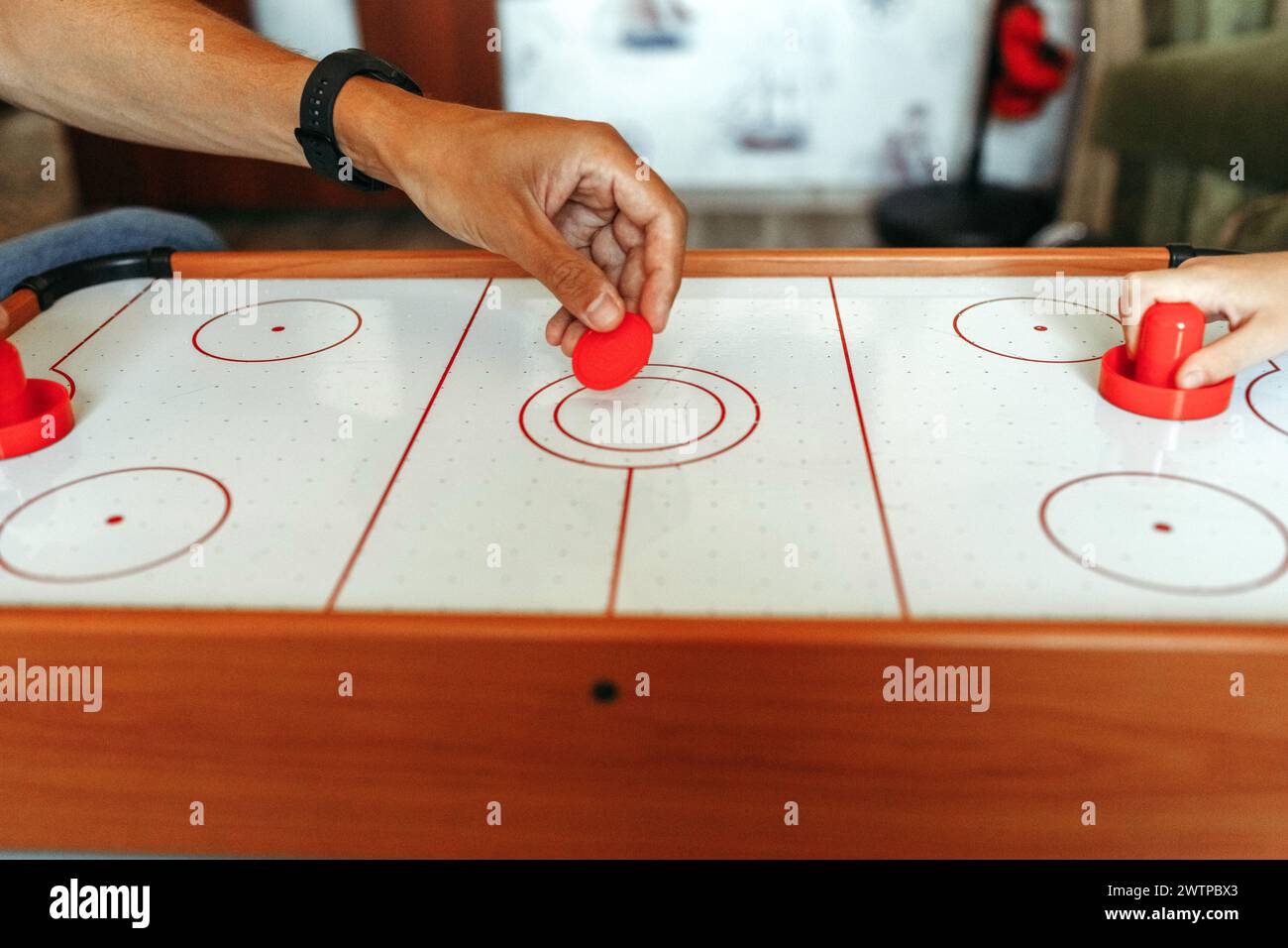 Zwei Personen spielten ein Air-Hockey-Spiel und schlugen geschickt den Puck mit Paddeln auf einer glatten Tischfläche. Stockfoto