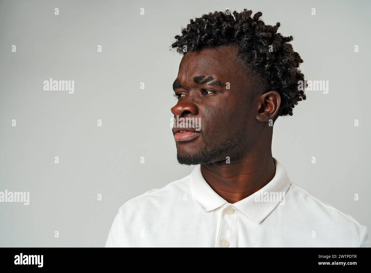 Afrikanischer Mann in weißem Hemd, der seitlich aussieht Stockfoto