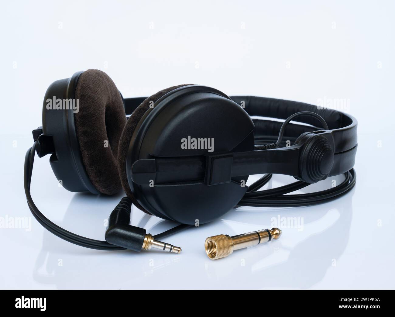 Professionelle schwarze DJ-Kopfhörer mit Velor-Ohrpolstern und vergoldetem 6,3-mm-Klinkenadapter auf weißem Hintergrund mit Reflexion Stockfoto