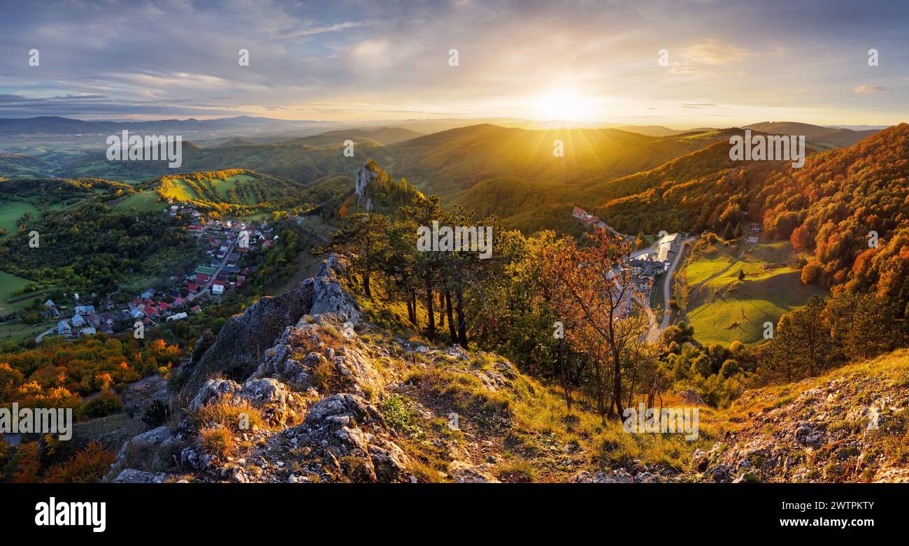 Berge bei Sonnenuntergang in der Slowakei - Vrsatec. Landschaft mit Berghügeln, Orangenbäumen und Gras im Herbst, farbenfroher Himmel mit goldenen Sonnenstrahlen. Panorama Stockfoto