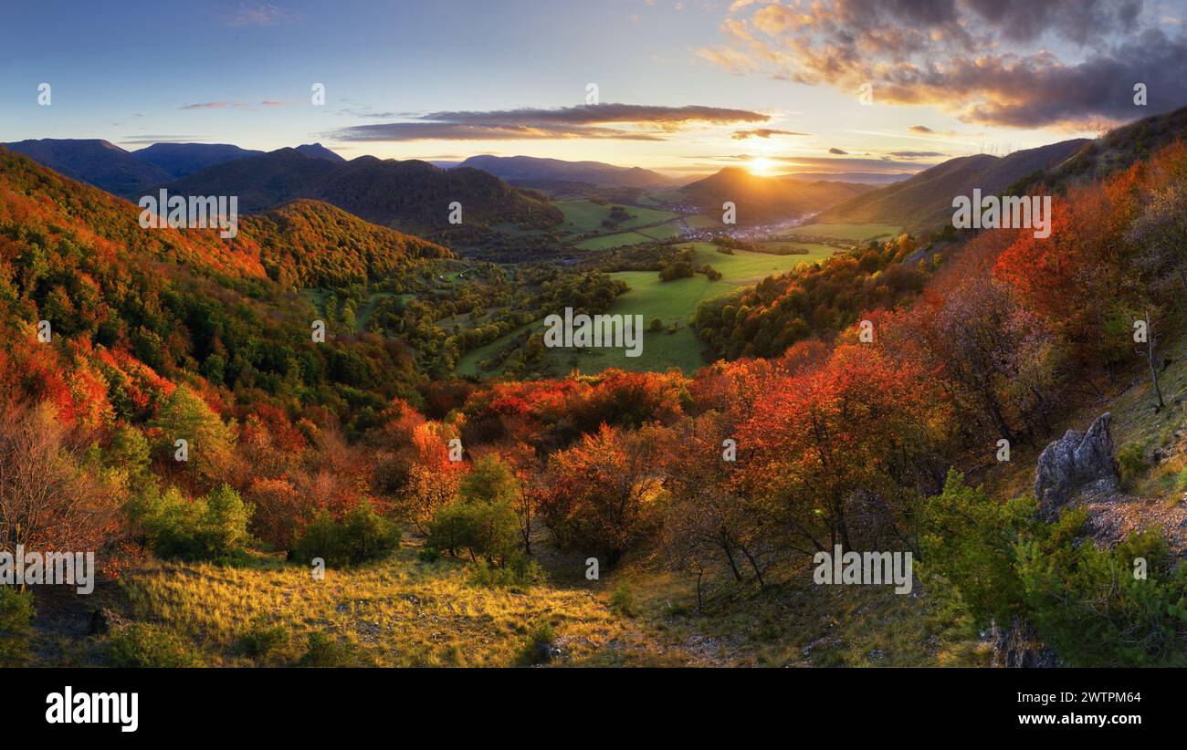 Berge bei Sonnenuntergang in der Slowakei. Landschaft mit Berghügeln, Orangenbäumen und Gras im Herbst, farbenfroher Himmel mit goldenen Sonnenstrahlen. Panorama Stockfoto