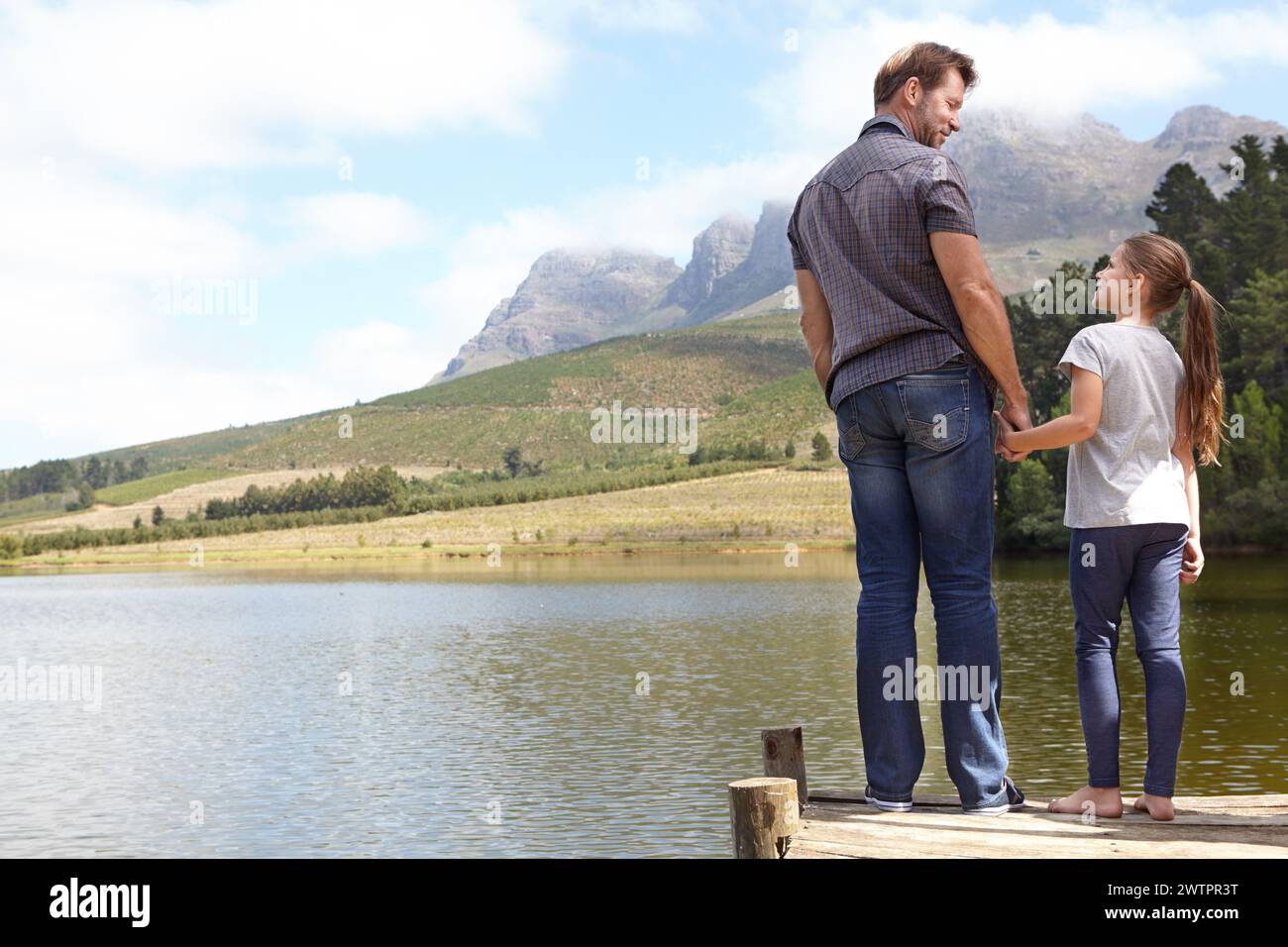 Vater, Tochter und Hände halten mit Pier am See, verbinden sich in der Natur mit Urlaub, Reise und Familie. Liebe, Unterstützung und Vertrauen, Mann und jung Stockfoto