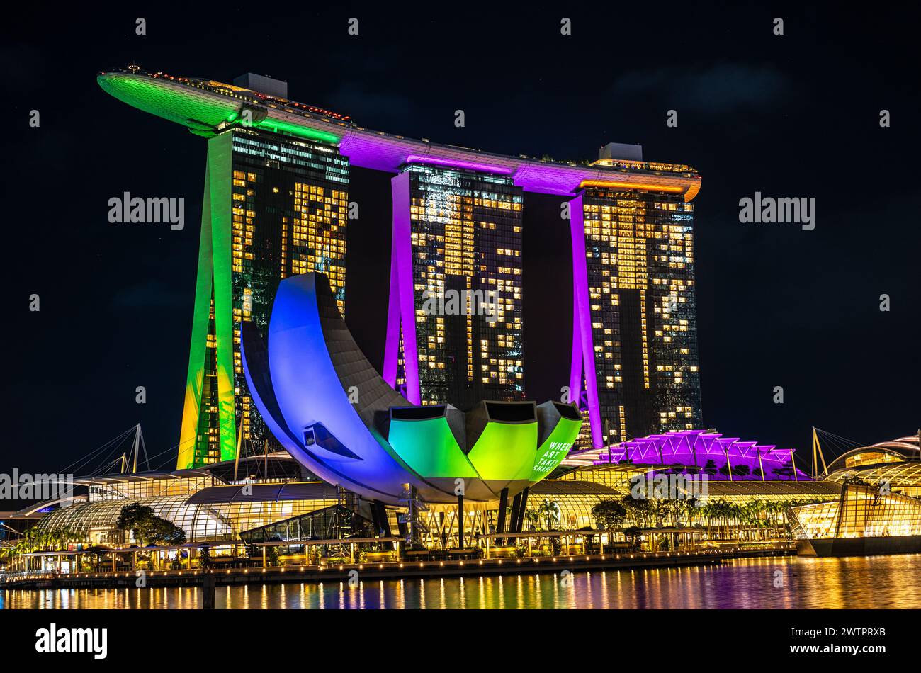 Singapur, 24. Januar 2024: Das Marina Bay Sands Hotel in Singapur ist nachts hell und reflektiert im Wasser. ArtScience Museum und Stockfoto