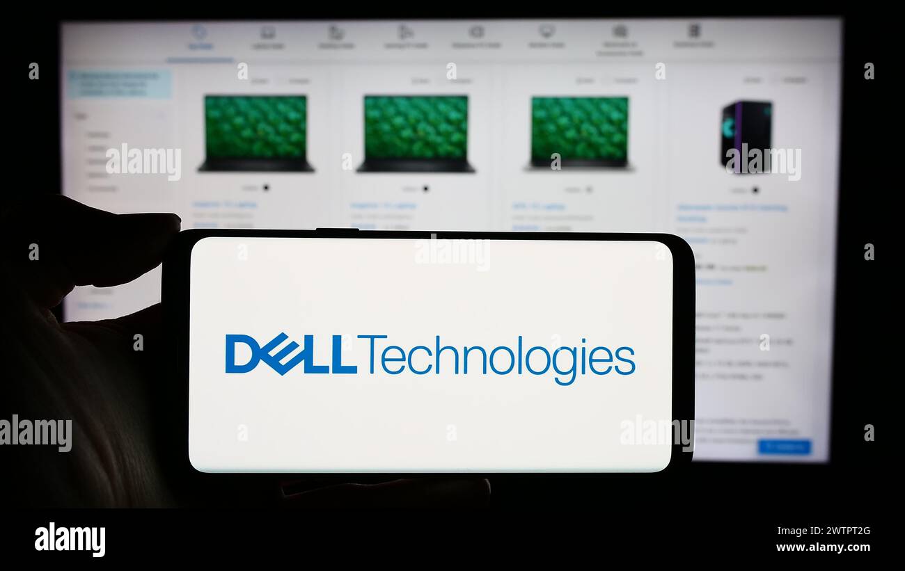 Person, die ein Mobiltelefon mit dem Logo des US-Technologieunternehmens Dell Technologies Inc. Vor der geschäftlichen Website hält. Schwerpunkt auf dem Display des Telefons. Stockfoto