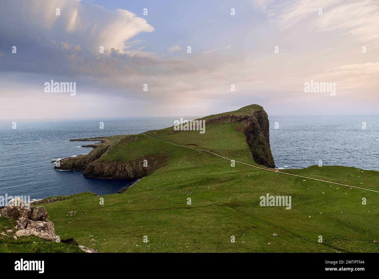 Neist Cliff auf der Isle of Skye präsentiert eine atemberaubende Landschaft, in der grüne Hänge unter einem dramatischen Himmel auf das weite Meer treffen Stockfoto